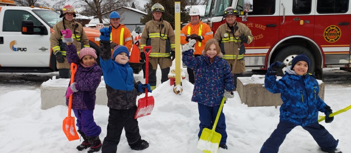 Photo of children after clearing snow near fire hydrant.