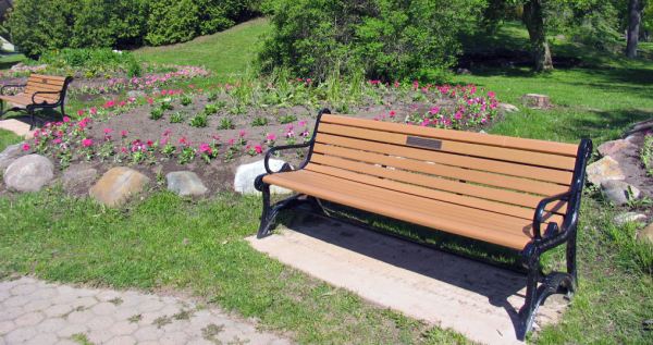 Vibrant flower beds next to a commemorative bench