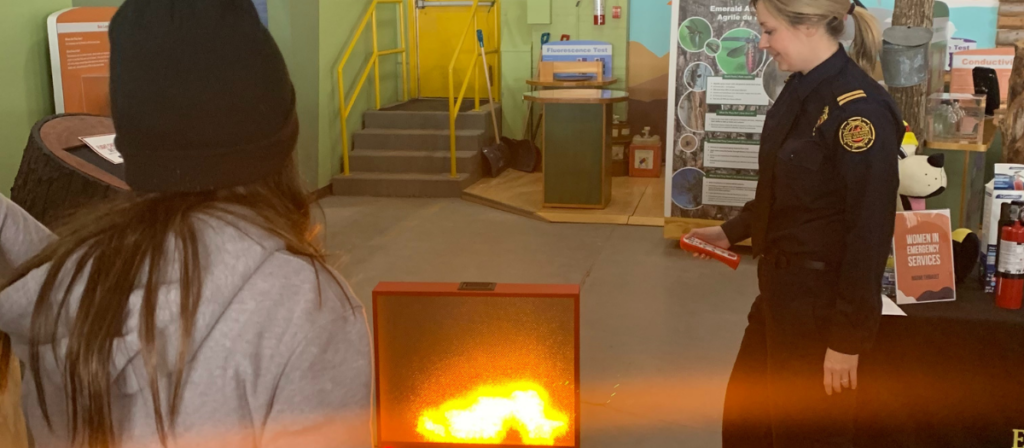 A firefighter demonstrates fire extinguisher techniques to her audience