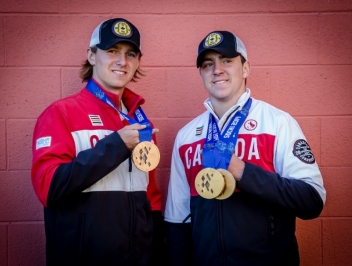 Two men posing for a photo with three Olympic medals